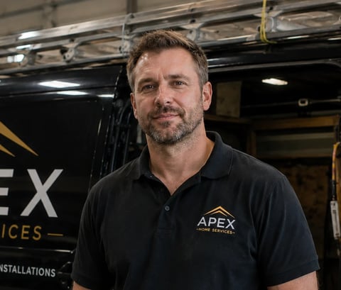 Man in black APEX polo shirt standing in front of vehicle in garage setting